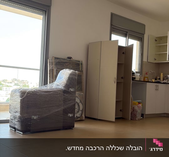 רהיטים עטופים בניילון בחדר ריק עם ארונות פתוחים